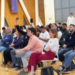Público diverso acompanha atentamente uma atividade formativa em ambiente interno.