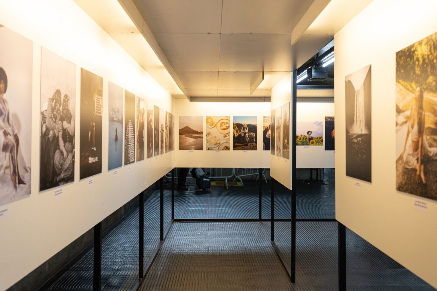 Galeria de arte iluminada com fotografias expostas em painéis nas paredes