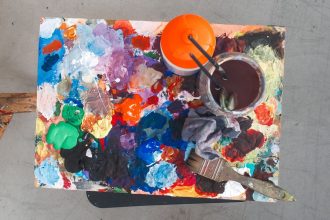 Paleta de artista com tintas de várias cores e pincéis, representando o processo de criação artística