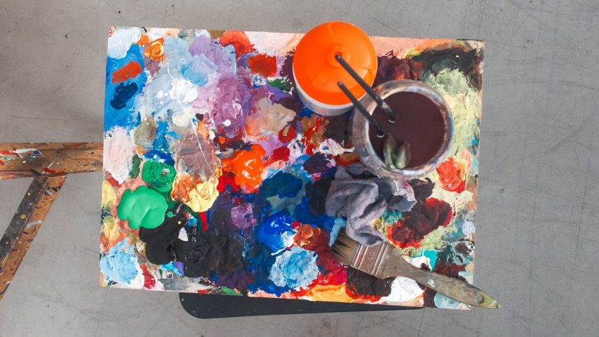 Paleta de artista com tintas de várias cores e pincéis, representando o processo de criação artística
