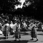 Dançarinos com trajes tradicionais se apresentam diante do público em uma celebração cultural ao ar livre.