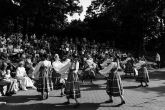 Dançarinos com trajes tradicionais se apresentam diante do público em uma celebração cultural ao ar livre.
