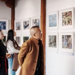 Visitantes observam fotografias expostas nas paredes de uma galeria de arte.