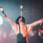 Artista circense equilibra e lança claves durante uma apresentação teatral.