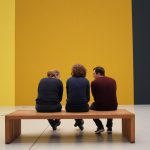 Visitantes observam obras expostas em uma galeria de arte.